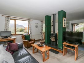 A living room with a wood stove and television at Geryllan, Rhandirmwyn near Llandovery