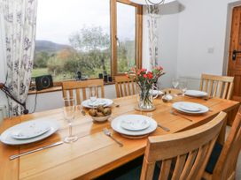 A dining room with a wooden table and chairs at Geryllan Rhandirmwyn near Llandovery