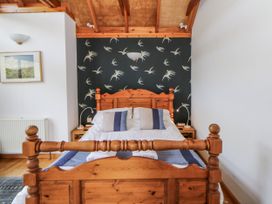 A bedroom with a wooden bed and bedside table at Geryllan Rhandirmwyn near Llandovery