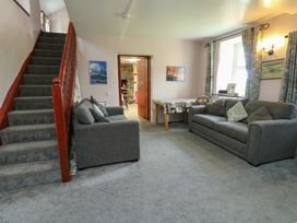 A living room with a staircase, sofas and a table at Glan y Gors in Dinorwic near Llanberis