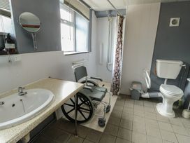 A bathroom with a sink, toilet, shower, and wheelchair at Glan y Gors in Dinorwic near Llanberis