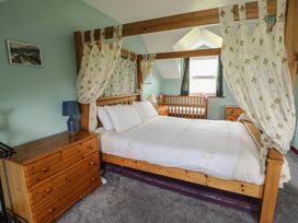 A bedroom featuring a four-poster bed and a baby crib at Glan y Gors in Dinorwic near Llanberis