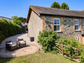 An outdoor seating area with chairs and a table near a stone wall at Peniarth in Penybontfawr near Oswestry