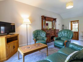 A living room with green furniture and a television at Peniarth in Penybontfawr near Oswestry