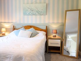 A bedroom with a bed, nightstand, mirror, and wall art at Peniarth in Penybontfawr near Oswestry