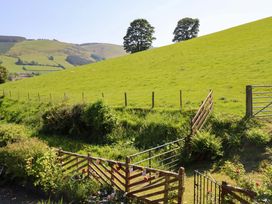 A view of a green hill with trees and a wooden gate near Peniarth in Penybontfawr near Oswestry