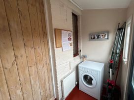 A utility room with a washing machine and corkboard at Sea Lily in New Haggerston near Holy Island