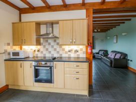 A kitchen with a stove and microwave adjacent to a living area at Y Bwthyn in Swyddffynnon near Pontrhydfendigaid