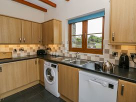 A kitchen with cabinets, sink, washing machine, and dishwasher at Y Bwthyn in Swyddffynnon near Pontrhydfendigaid