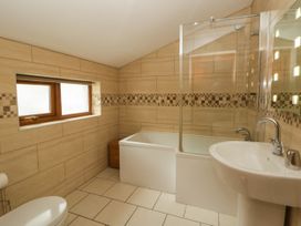 A bathroom with a bathtub, shower, sink, and window at Y Bwthyn in Swyddffynnon near Pontrhydfendigaid