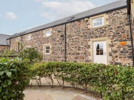 An exterior view of a stone building with windows and a door at Granary Stone House in Embleton