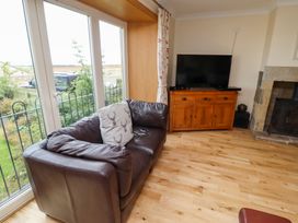 A living room with a sofa and television at Granary Stone House in Embleton