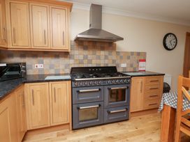 A kitchen with an oven, cabinets and a microwave at Granary Stone House in Embleton