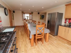 A kitchen with a dining table and refrigerator at Granary Stone House Embleton