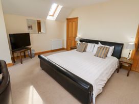 A bedroom with a bed and TV at Granary Stone House Embleton