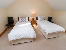 A bedroom with two single beds and a nightstand at Granary Stone House in Embleton