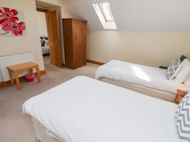 A bedroom with two beds and a wardrobe at Granary Stone House in Embleton
