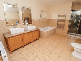 A bathroom with two sinks, a bath and a shower at Granary Stone House in Embleton