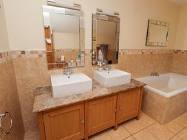 A bathroom with double sinks and a bath tub at Granary Stone House in Embleton