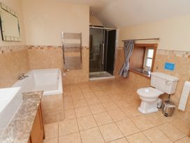 A bathroom with a shower, bath tub, sink and toilet at Granary Stone House Embleton