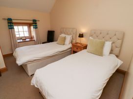 A bedroom with two single beds and a window at Granary Stone House in Embleton