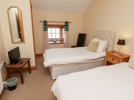 A bedroom with two beds and a television at Granary Stone House in Embleton