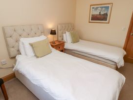 A bedroom with two beds and a bedside table at Granary Stone House in Embleton