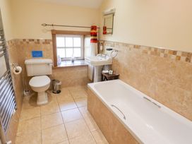 A bathroom with a bathtub, toilet, and sink at Granary Stone House in Embleton