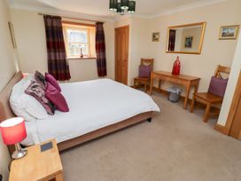A bedroom with a bed, table, chairs, and a mirror at Granary Stone House, Embleton