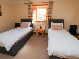 A bedroom with two beds and a table at Granary Stone House Embleton