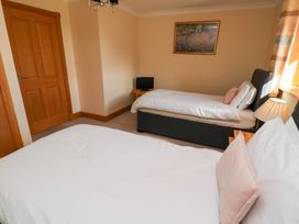 A bedroom with two beds and a television at Granary Stone House in Embleton
