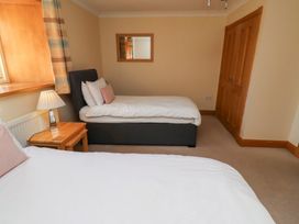 A bedroom with two beds and a nightstand at Granary Stone House in Embleton