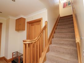A staircase with wooden handrail in a hallway at Granary Stone House in Embleton