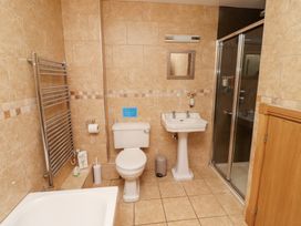 A bathroom with a bathtub, toilet, sink, and shower at Granary Stone House in Embleton