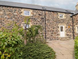 An outdoor view of a stone house with garden features at Granary Stone House in Embleton