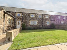 A stone building with windows and a door in a garden at Granary Stone House in Embleton