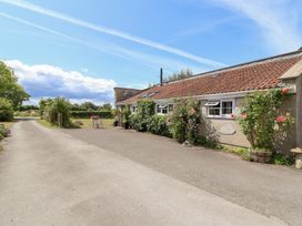 An outdoor area featuring a driveway and flowering plants at Pear Tree Cottage Mark near Burnham-on-Sea