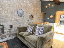 A living room with a sofa, clock, and mirror at Pear Tree Cottage Mark near Burnham-on-Sea