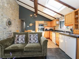 A kitchen with wooden cabinets and a sofa at Pear Tree Cottage Mark near Burnham-on-Sea