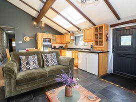 A kitchen with wooden cabinets and a sofa at Pear Tree Cottage Mark near Burnham-on-Sea