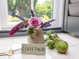 A flower vase and fruits on a countertop at Pear Tree Cottage in Mark near Burnham-on-Sea