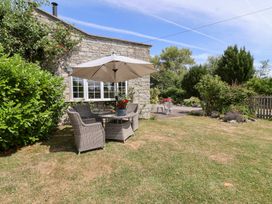 A seating area with chairs and a table under an umbrella at Pear Tree Cottage Mark near Burnham-on-Sea
