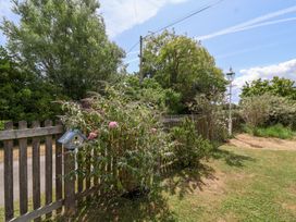 A garden with a fence and birdhouse at Pear Tree Cottage Mark near Burnham-on-Sea
