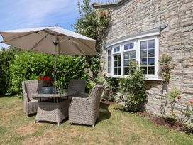 A garden with a table and chairs under an umbrella at Pear Tree Cottage in Mark near Burnham-on-Sea