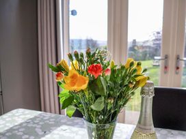 A dining room table with a flower vase and prosecco at Heather Croft in Robin Hood's Bay