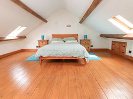 A bedroom with a bed between two nightstands under slanted ceilings with wooden beams at Garreg Wen Isaf Bach in Penygroes near Caernarfon