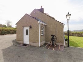 The exterior corner of a pebble dash house with a white door a window a black lamp post and an old metal machine on a stone slab at Garreg Wen Isaf Bach in Penygroes near Caernarfon
