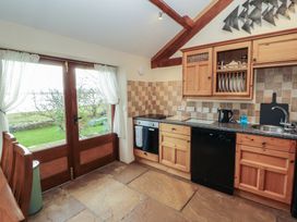 A kitchen with wooden cabinets and appliances at Sonya's Cottage in Anthorn, Solway Firth