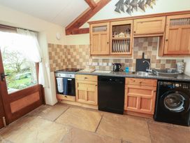 A kitchen with wooden cabinets and appliances at Sonya's Cottage in Anthorn, Solway Firth