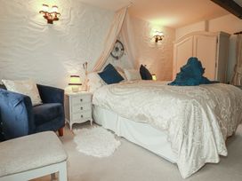 A bedroom with a bed and armchair at Poldark Cottage East Taphouse